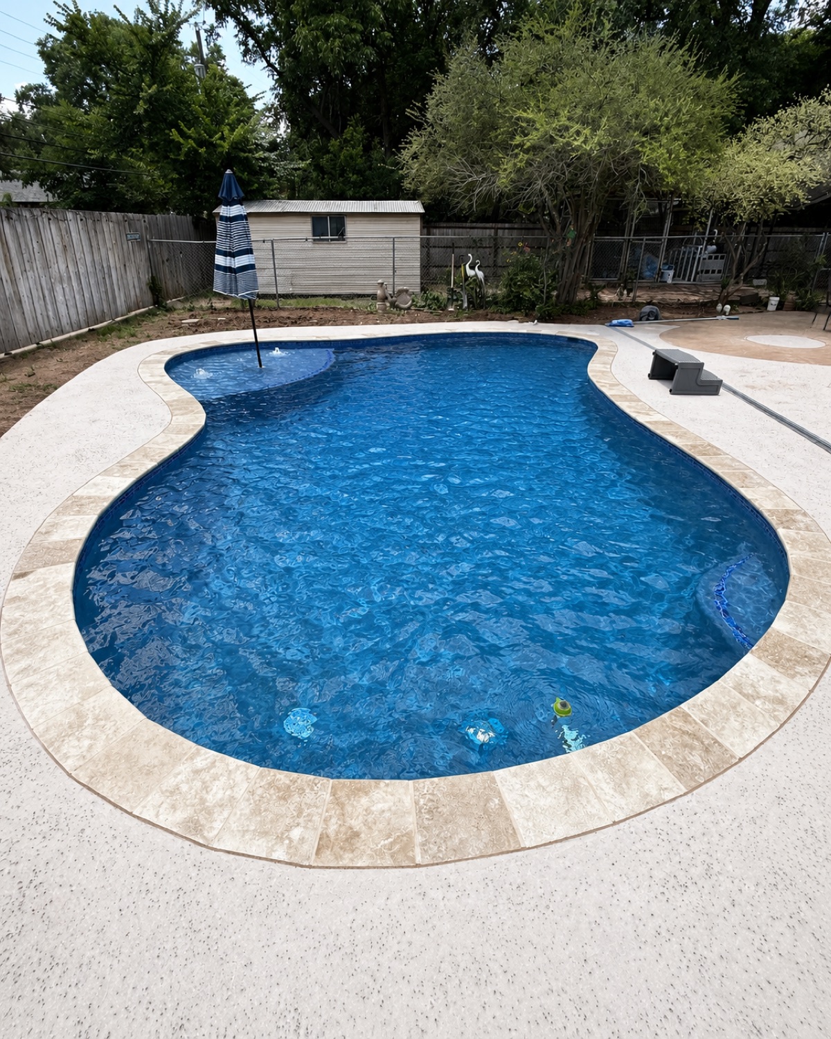 Finished freeform pool with a travertine deck