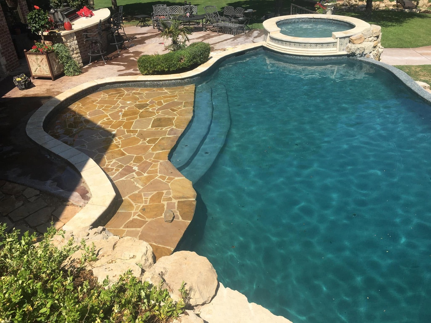 Freeform pool with flagstone tanning ledge and round raised spa